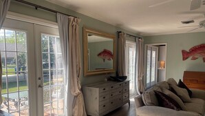 A room with a large window, a mirror, a dresser, and a sofa.