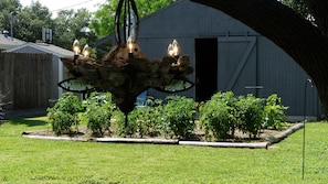 Un jardin agrémenté d’un lustre original qui en constitue l’élément central, entouré de diverses plantes et d’une clôture en bois.