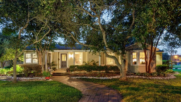 A two-story house with a brick pathway leading to the front door, surrounded by well-maintained lawns and trees.