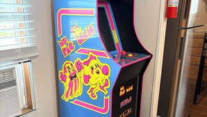 A brightly colored arcade machine with a cartoon character, located in a room with a refrigerator and a window with blinds. - Stay In Ohiopyle near The Falls & GAP trail. (Ohiopyle)