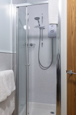 A glass-enclosed shower stall with a handheld showerhead and a wall-mounted control panel. - Morlea Bed & Breakfast (Inverness)
