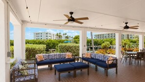 An outdoor patio area with seating arrangements and ceiling fans.