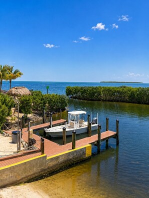 A boat docked at a pier with a clear view of the water and a distant island. - 4 Flr |2 Mastr |Oceanview |Jacuzzi |Beach |Marina (Tavernier)