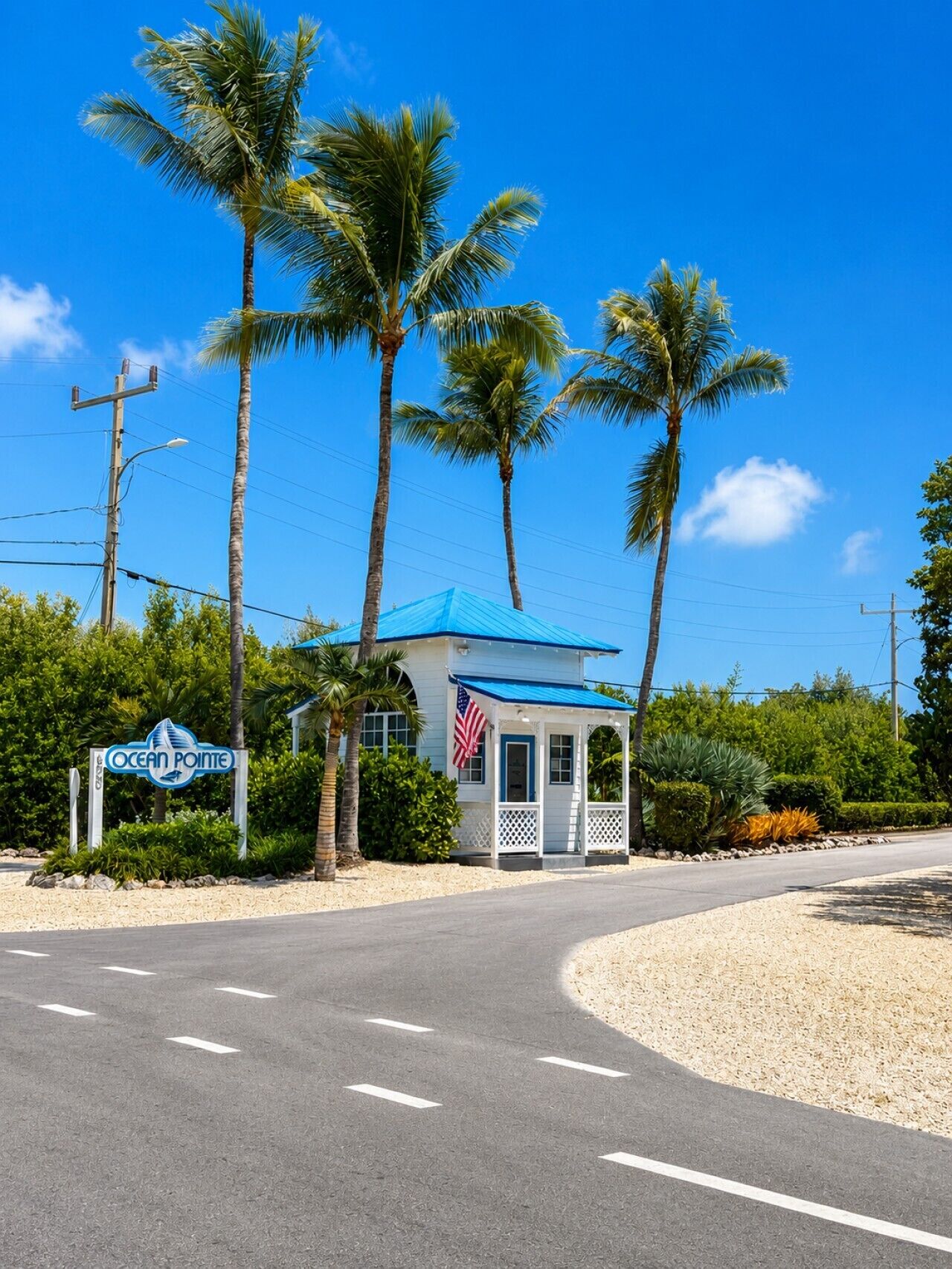 A small building with a blue roof and an American flag, surrounded by palm trees and a sign that reads 'Ocean Pointe'.