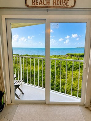 A beach house entrance with a view of the ocean and a balcony with a railing. - 4 Flr |2 Mastr |Oceanview |Jacuzzi |Beach |Marina (Tavernier)