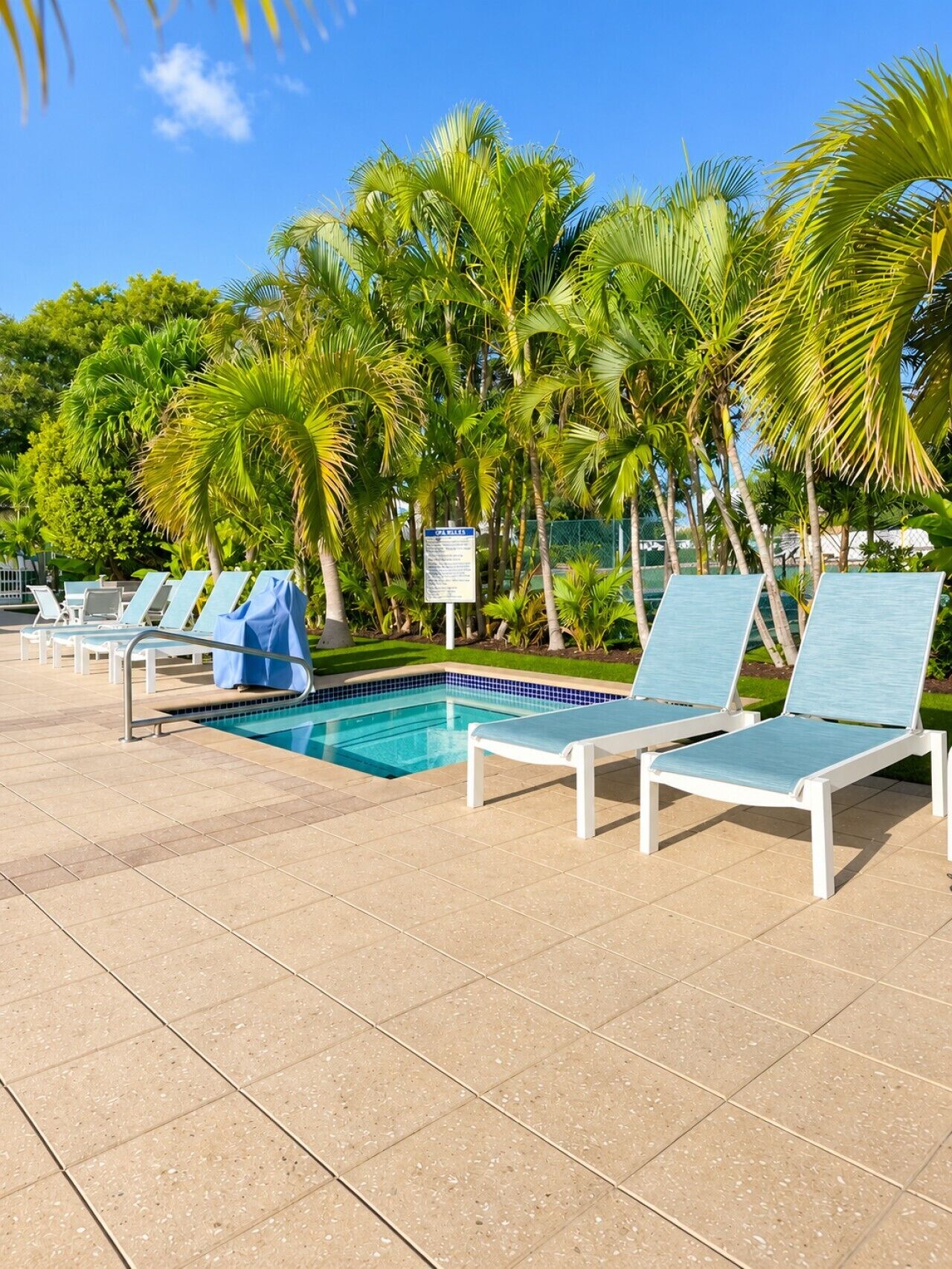 A poolside area with lounge chairs and a sign.