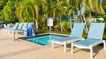 A poolside area with lounge chairs and a sign.