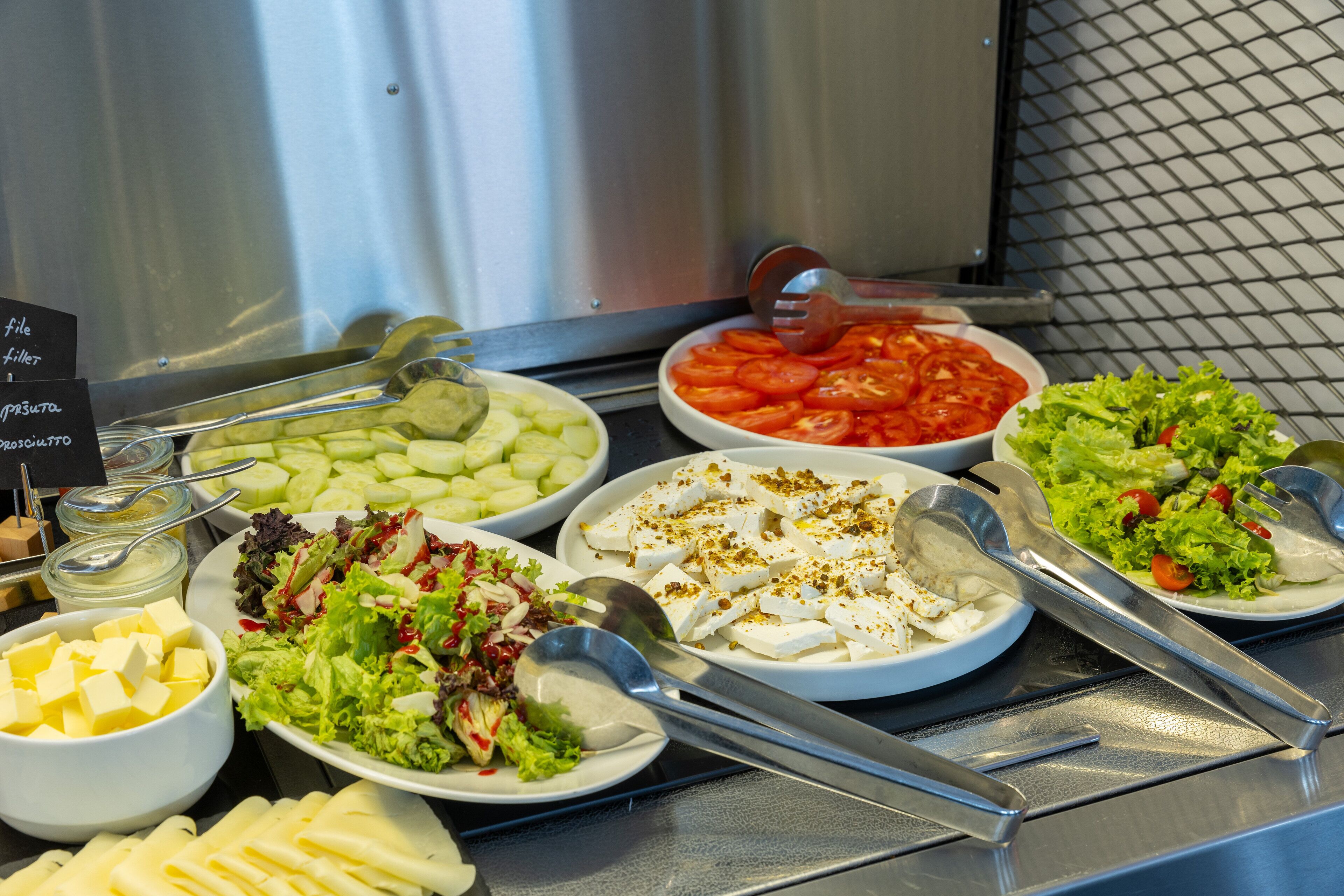 A buffet with various food items including salads, cheeses, and vegetables.