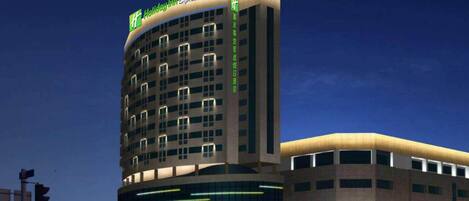 A multi-story hotel with a prominent 'Holiday Inn Express' sign, featuring a modern design with illuminated windows and a flat roof.