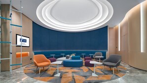 A modern lounge area with a circular ceiling design, comfortable seating, and a digital screen displaying information. - Holiday Inn Express Chongqing Airport Zone by IHG (Chongqing)