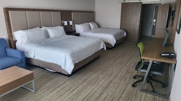 A hotel room with two beds, a desk, a chair, and a television.