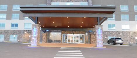 A Holiday Inn Express & Suites with a covered entrance, a crosswalk, and a parking area.