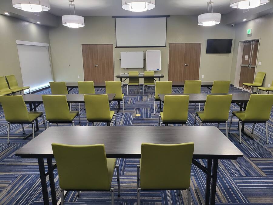 A conference room with tables and chairs, a projector screen, and a whiteboard.