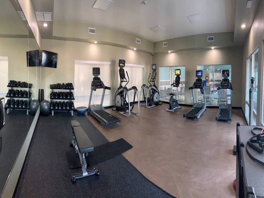Un gimnasio con cintas de correr, elípticas y pesas sueltas.