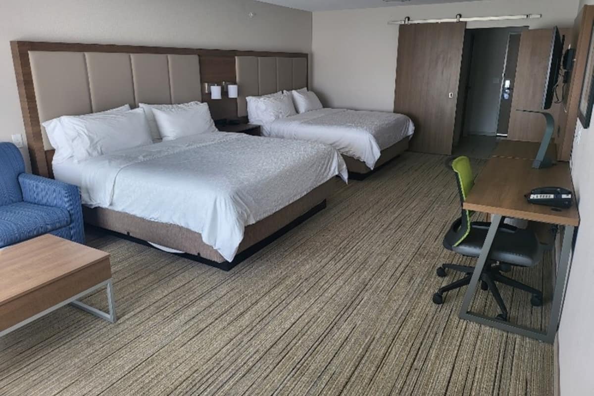 Ein Hotelzimmer mit zwei Betten, einem Schreibtisch, einem Stuhl und einem Fernseher.