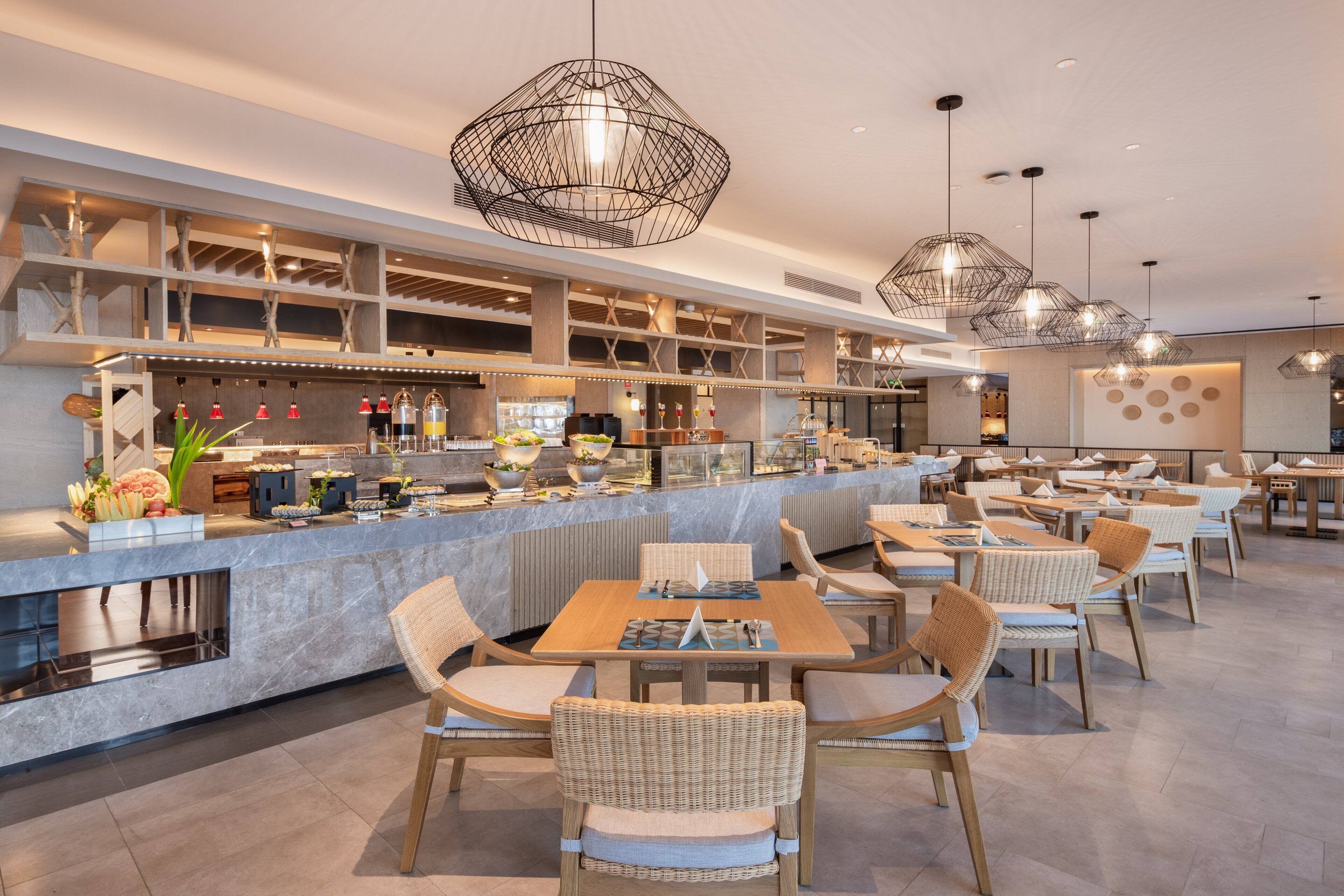 Ein modernes Restaurant mit einer langen Theke, Korbstühlen und Pendelleuchten.