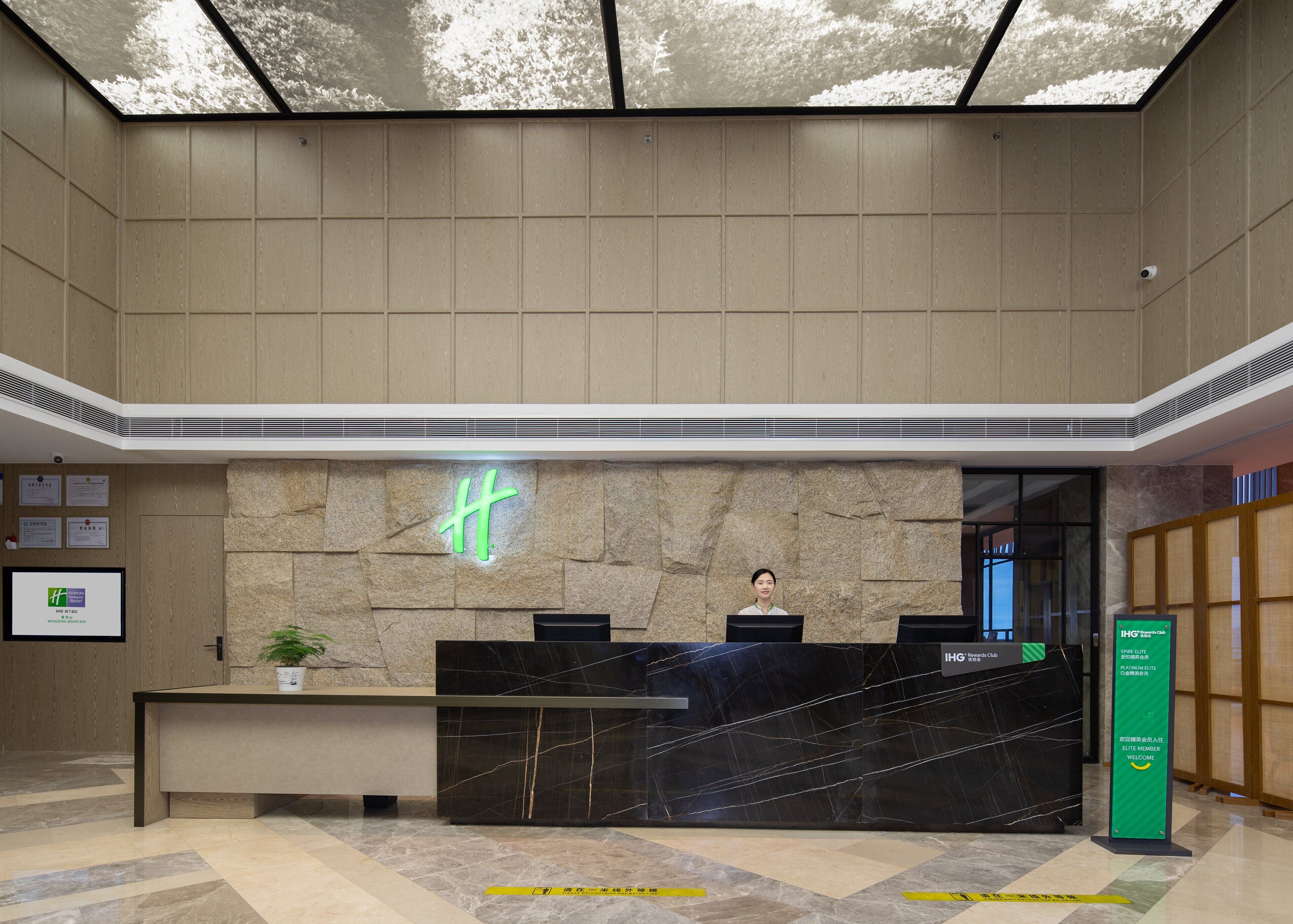 A reception desk with a stone wall backdrop, a neon sign, and a digital display.