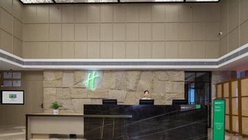 A reception desk with a stone wall backdrop, a neon sign, and a digital display.
