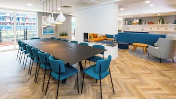 Un comedor moderno con una mesa grande, sillas color turquesa y un piso de madera con diseño de espiga.