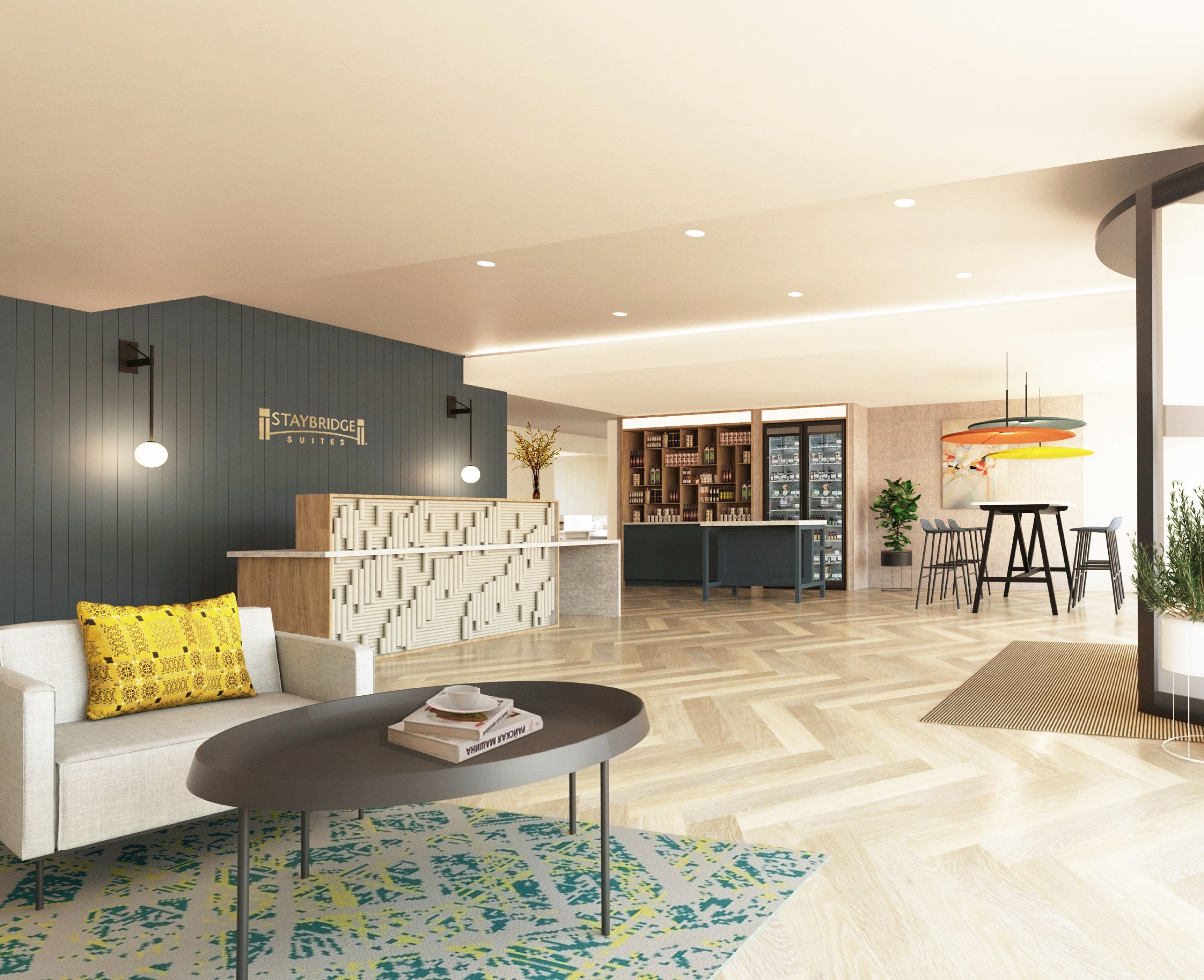 A modern hotel lobby with a reception desk, a seating area with a coffee table, and a bar.