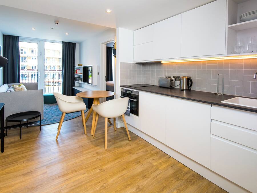 A modern kitchen with white cabinets, a wooden dining table, and chairs.