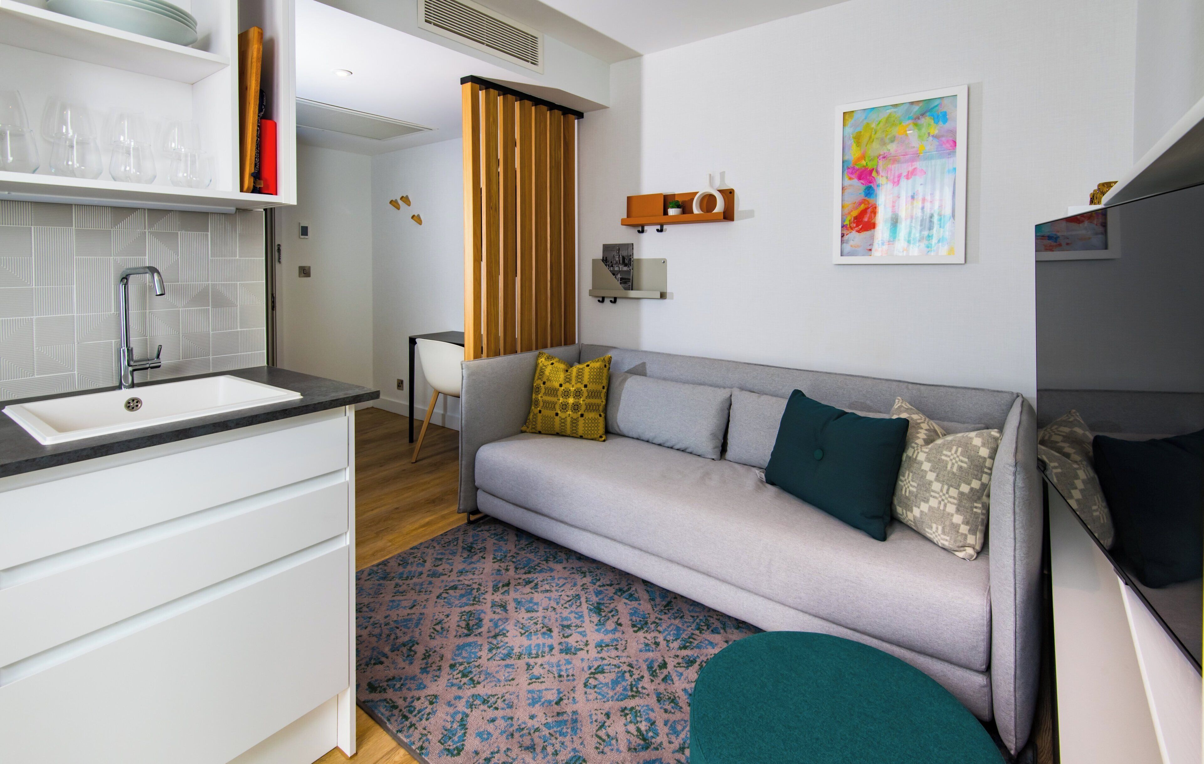 A modern living room with a sofa, a coffee table, and a kitchen area with a sink and cabinets.