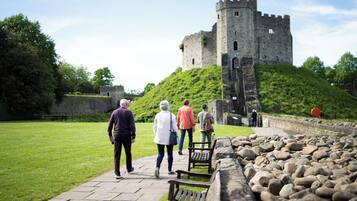 A castle with a stone wall and a grassy hill.