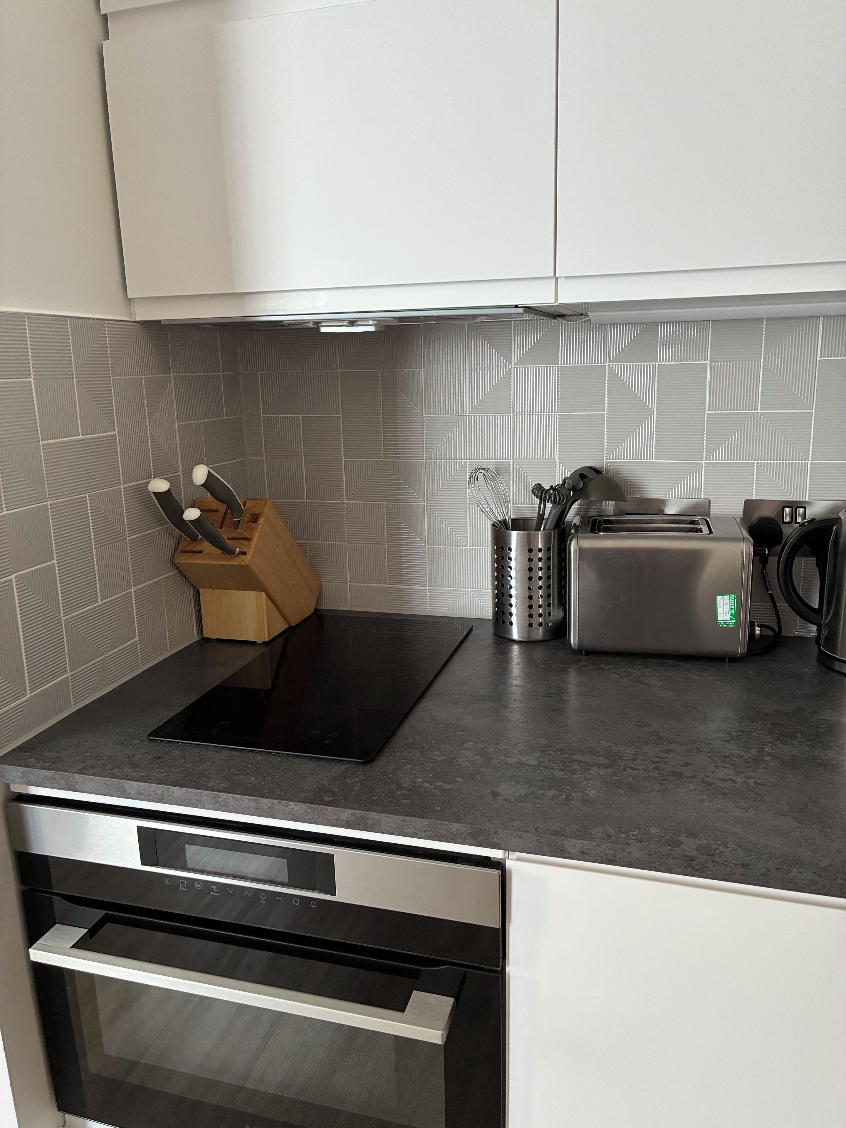 Eine Küche mit einer schwarzen Induktionskochplatte, einem Toaster und einer Kaffeemaschine.