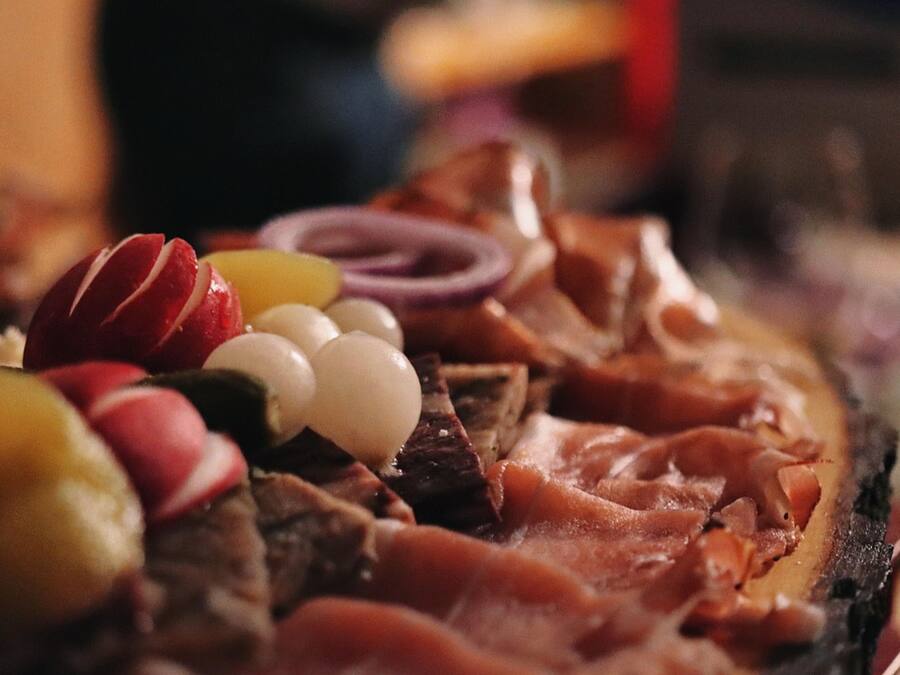 Gros plan d’une planche de charcuterie avec différents types de viandes, de fromages et de fruits.