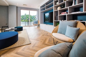 A modern living room with a large TV, comfortable seating, and a view of a river. - Staybridge Suites Cardiff by IHG (Cardiff)
