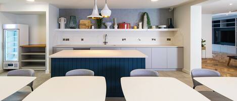 A modern kitchen with a central island, white cabinets, and a blue accent wall.