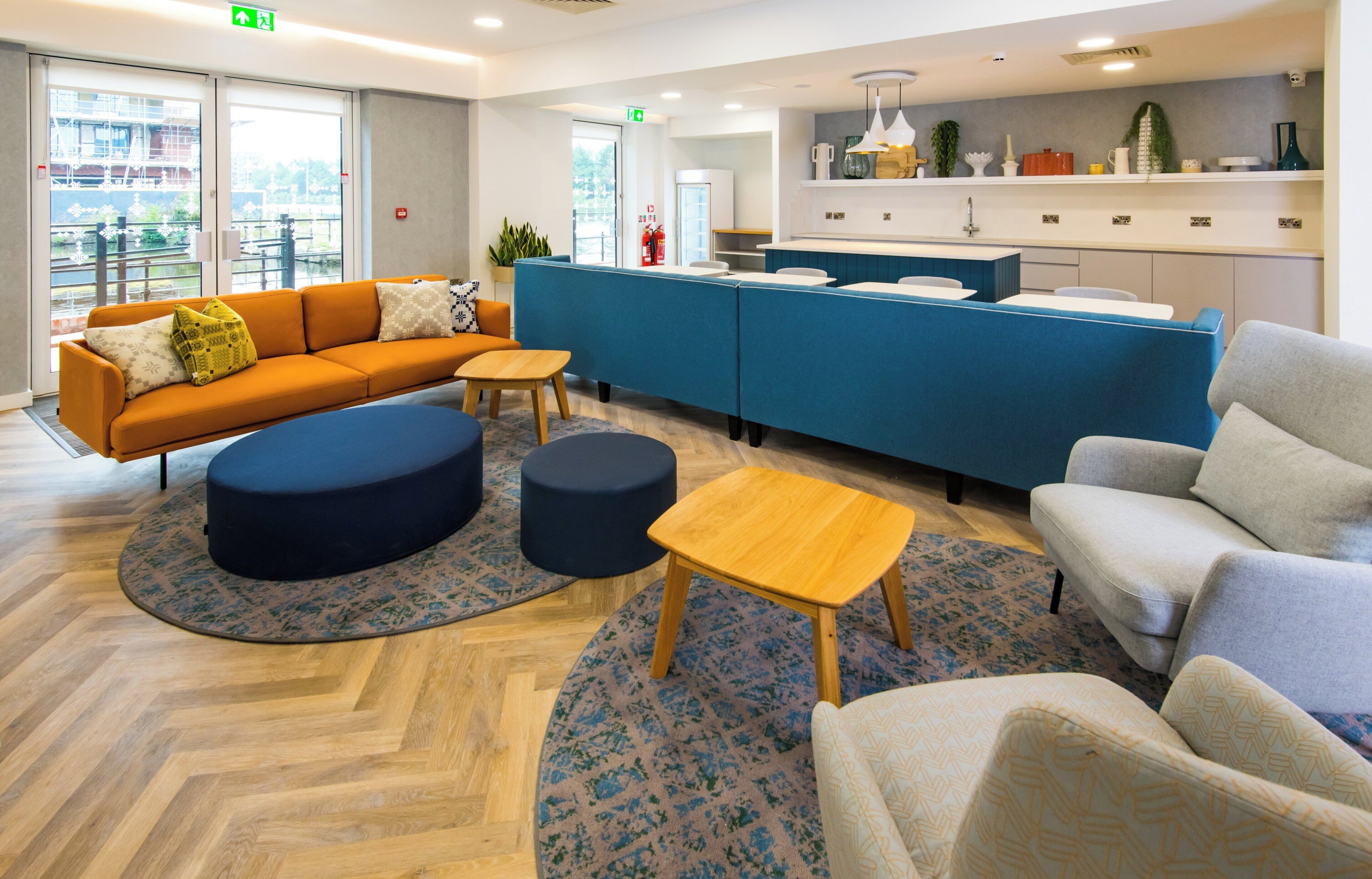 A modern hotel lobby with a reception desk, seating area, and a view of the outdoors.
