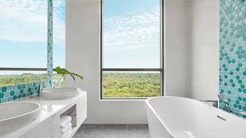 Un baño con dos lavamanos, una bañera y un amplio ventanal con vistas a un paisaje verde.