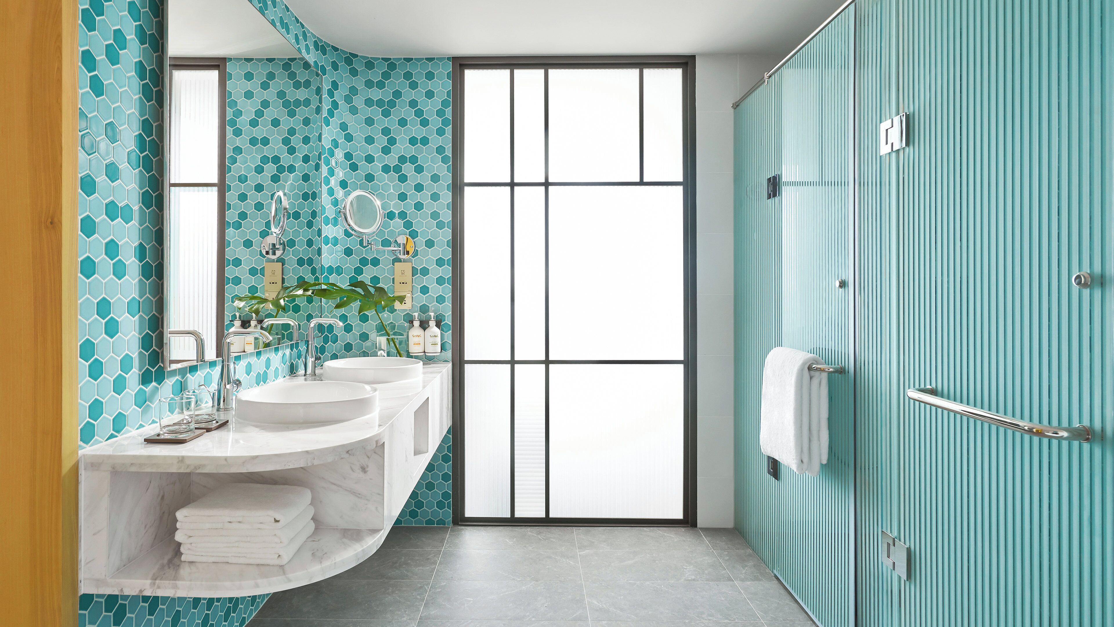 A bathroom with two sinks, a mirror, and a shower area.