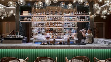 A bar area with a marble countertop, shelves of liquor bottles, and hanging spherical light fixtures.