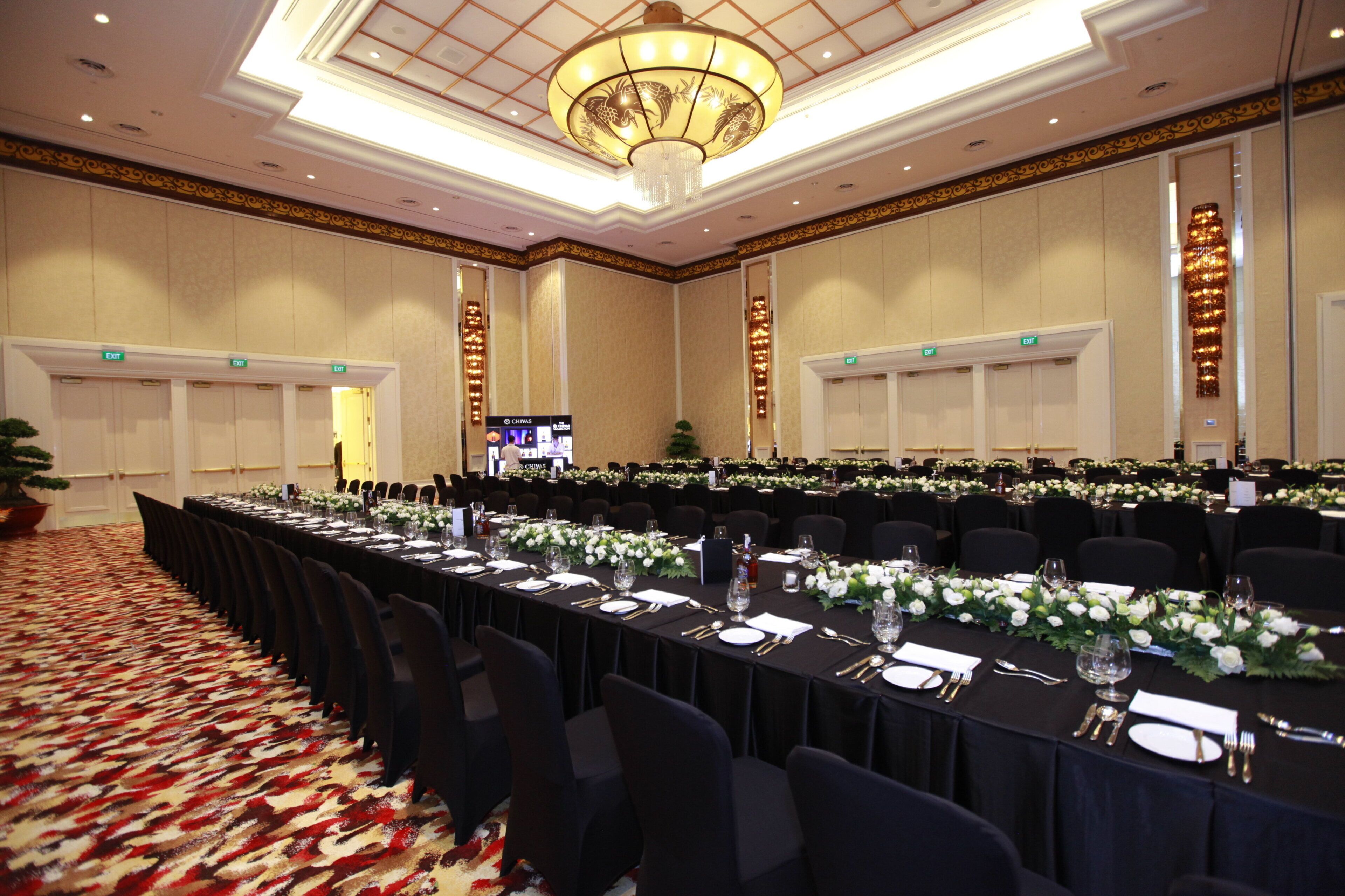 A conference room with long tables, chairs, and a chandelier.