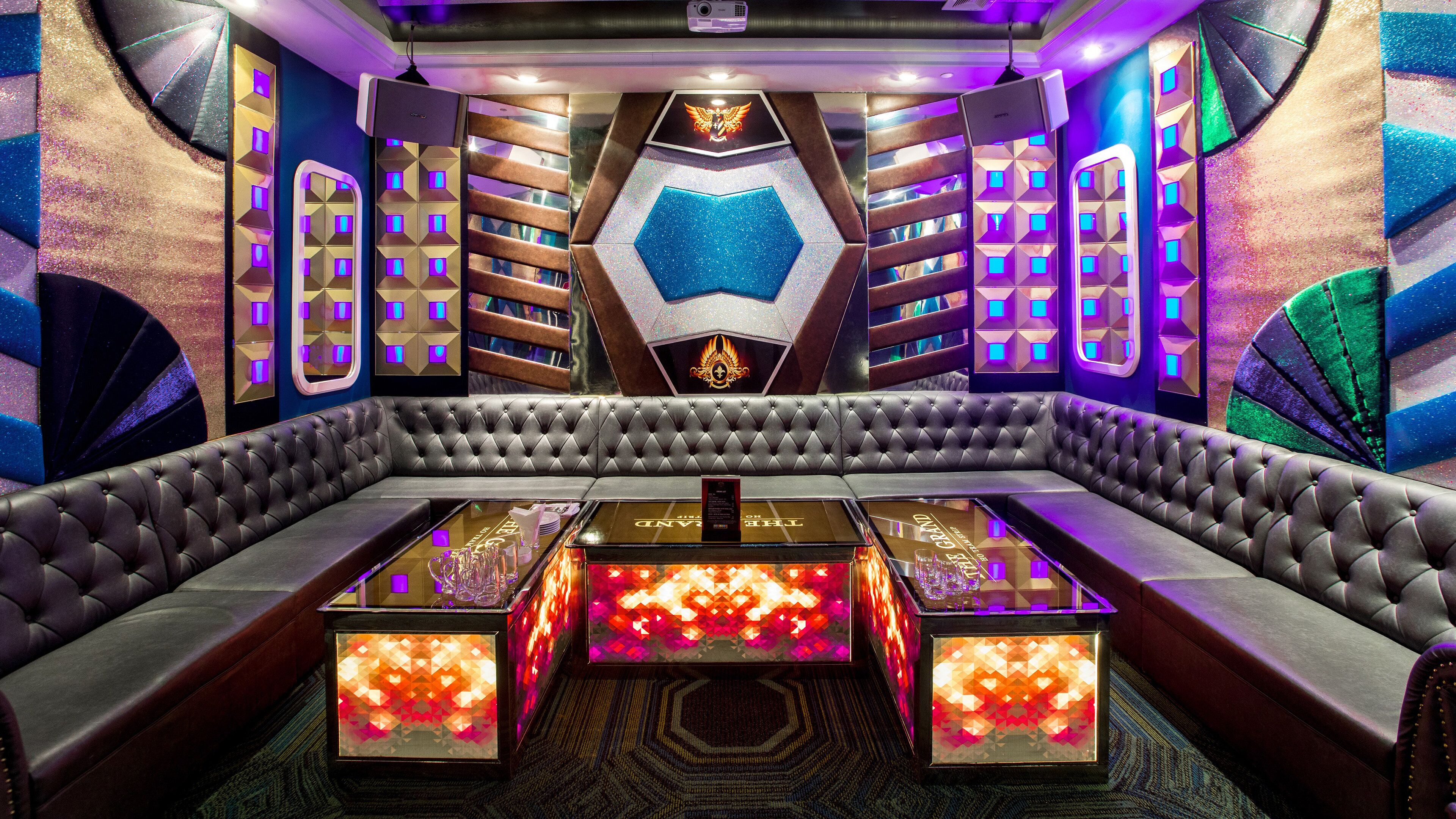 A luxurious room with a central seating area, decorative walls, and illuminated panels.