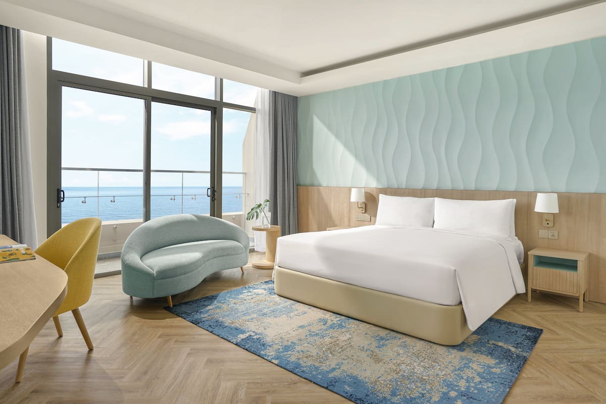 Ett hotellrum med ett stort fönster, en säng, ett skrivbord och en stol.