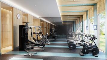 A gym with various exercise equipment, a mirrored wall, and a view of palm trees through large windows.