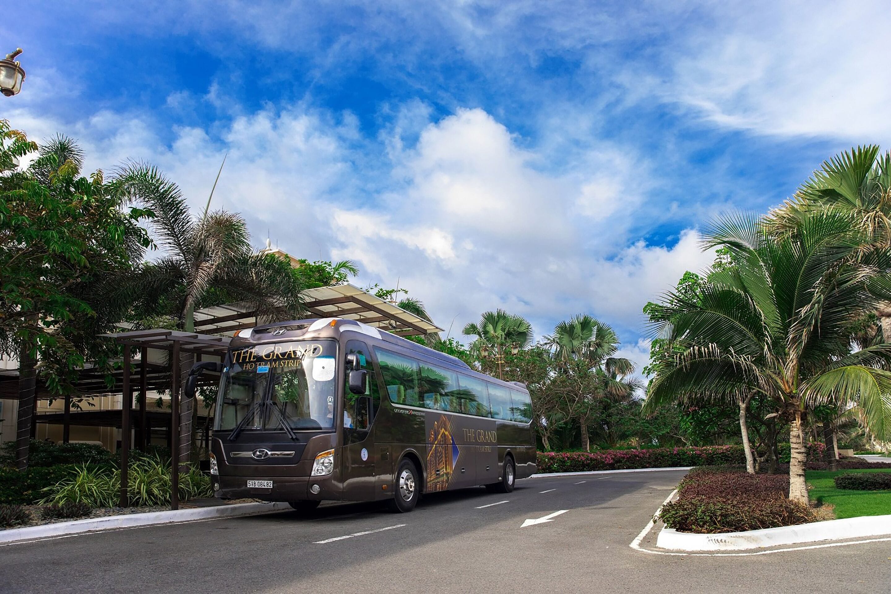 Een bus met de branding 'The Grand' geparkeerd bij een bushalte.