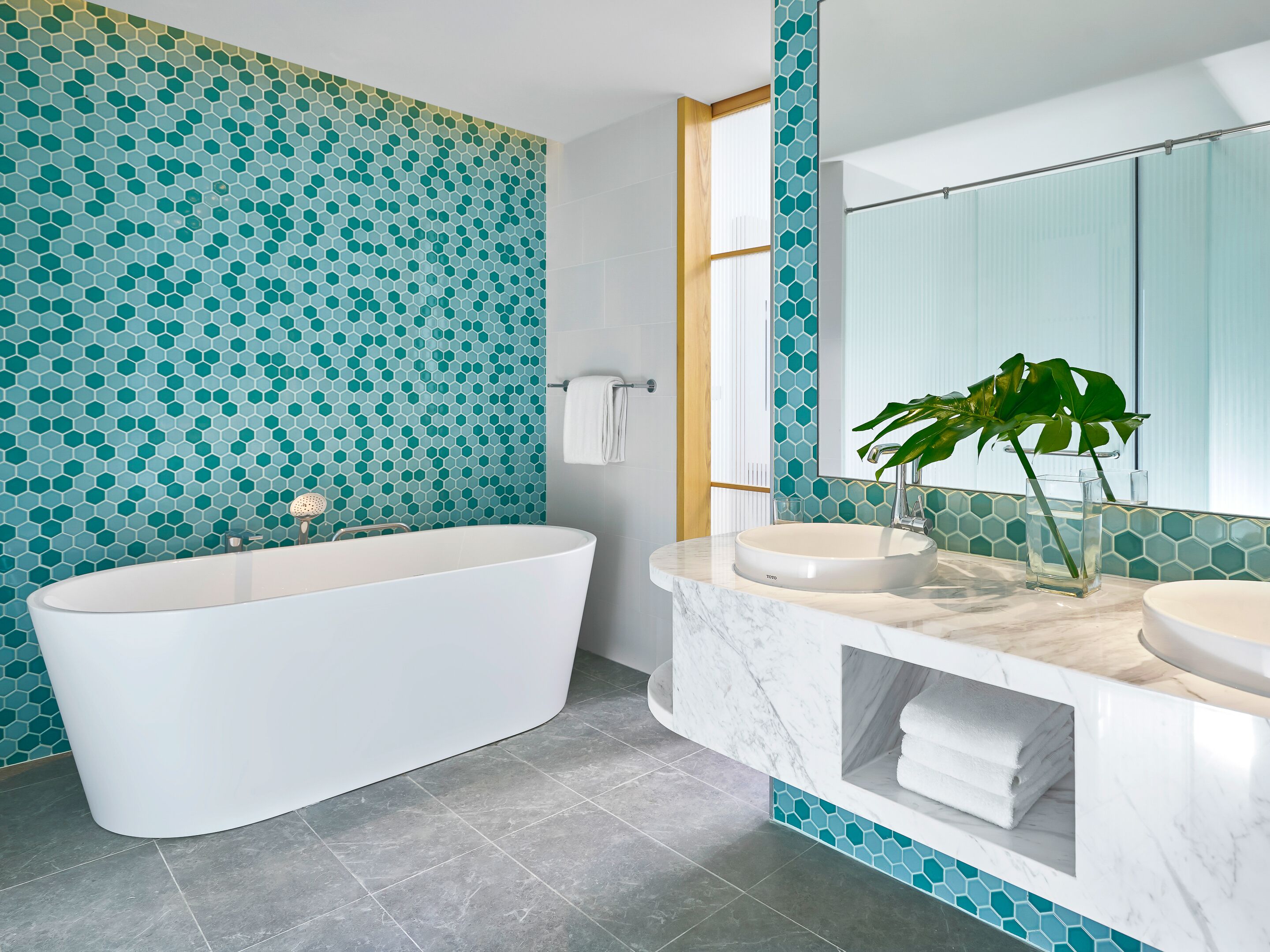Un baño moderno con una bañera independiente, dos lavamanos y un espejo grande.