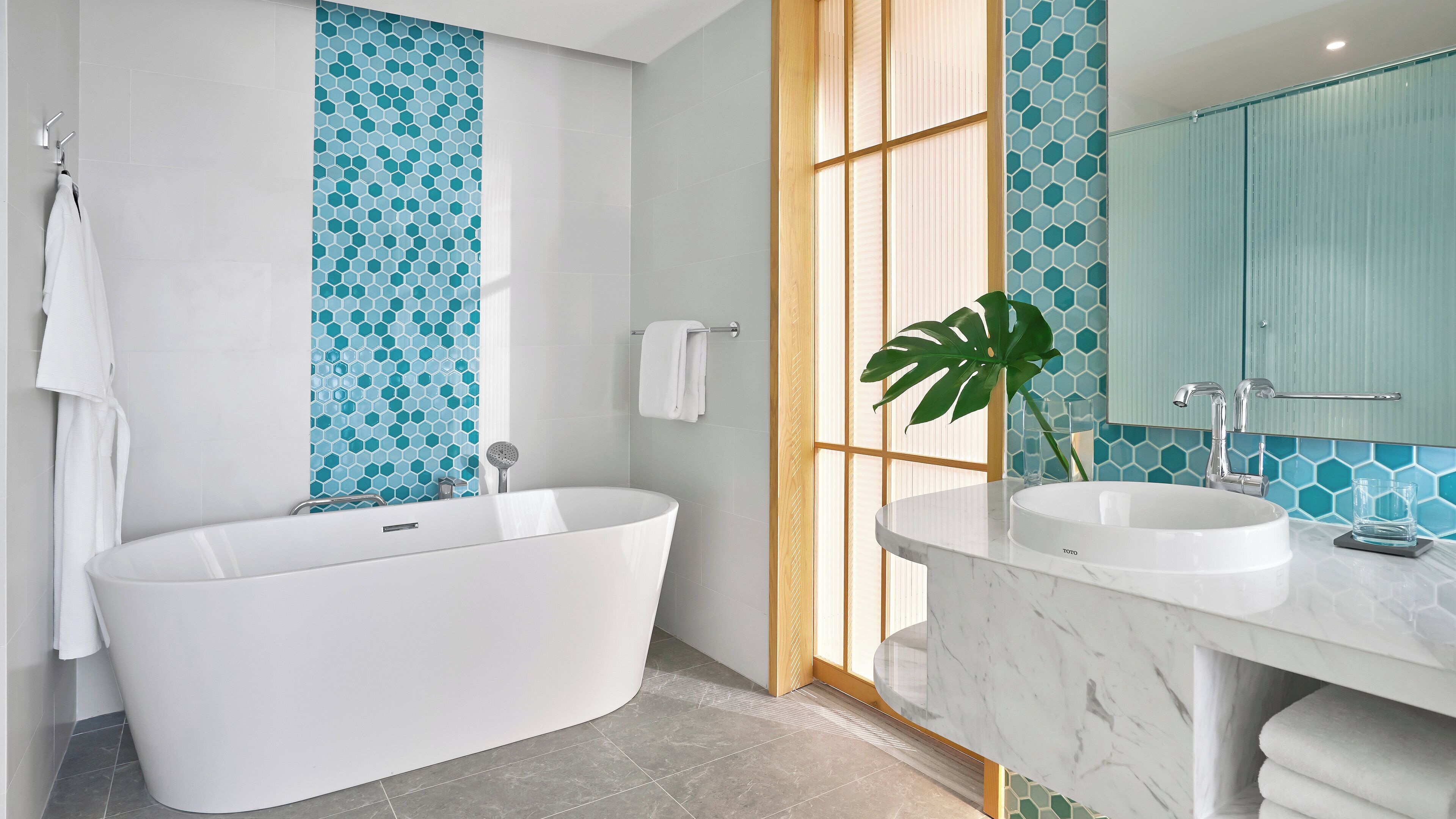 A modern bathroom with a freestanding bathtub, two sinks, and a large mirror.