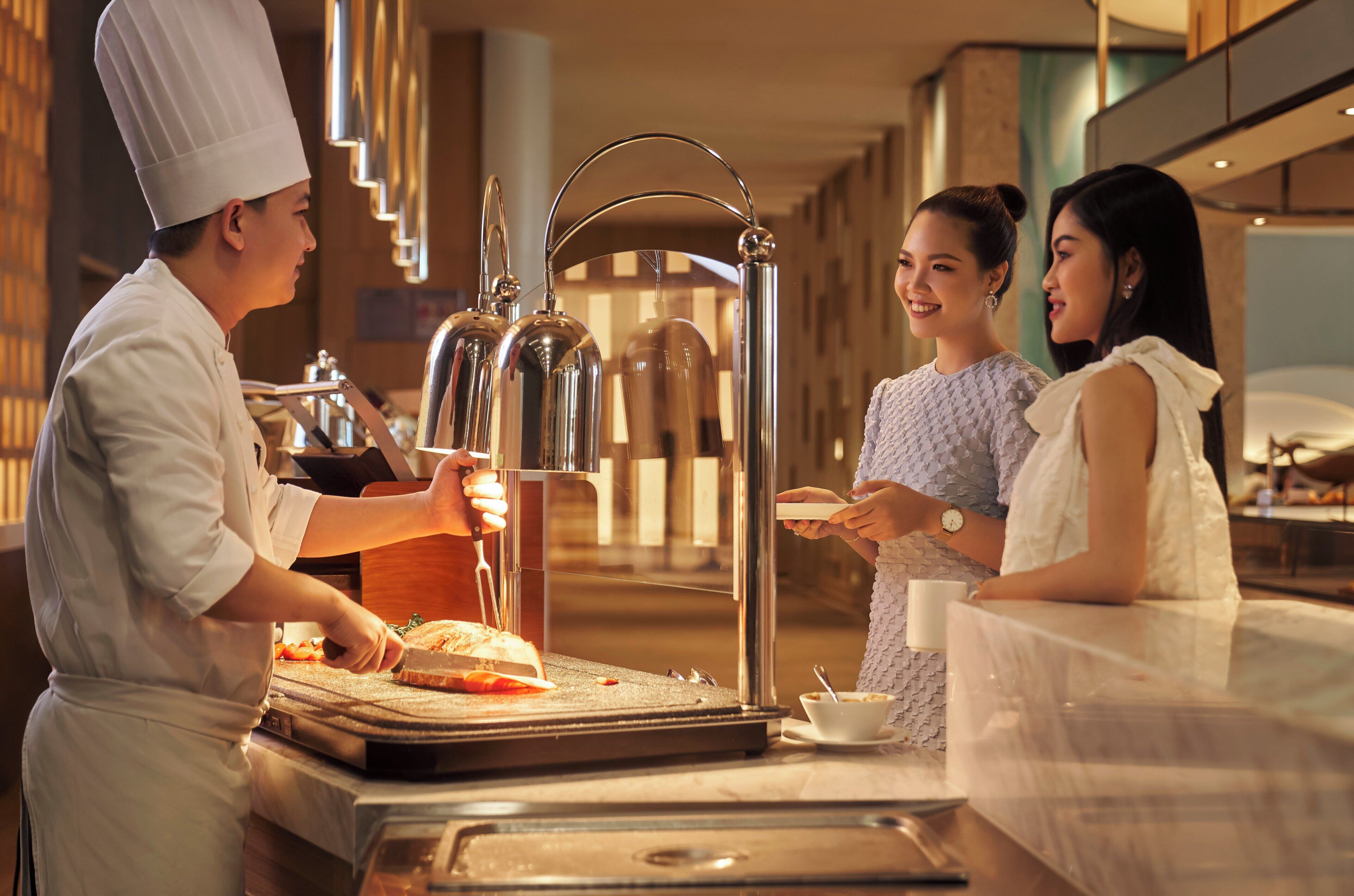 A chef preparing food in a modern kitchen with stainless steel appliances and a polished countertop.
