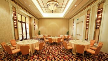 A conference room with round tables and chairs, a patterned carpet, and a decorative ceiling light.