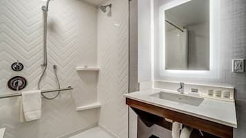 A modern bathroom with a shower, a vanity with a mirror, and a towel rack.
