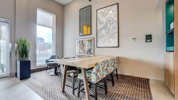 Una habitación de hotel moderna con un ventanal grande, un área de comedor con un tapete estampado y obras de arte en las paredes.