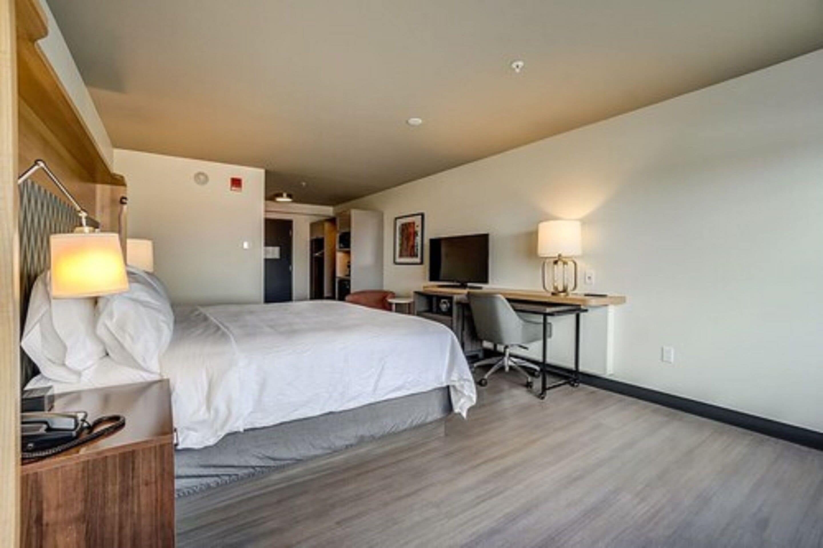 Une chambre d’hôtel équipée d’un lit, d’un bureau, d’une chaise et de deux lampes.