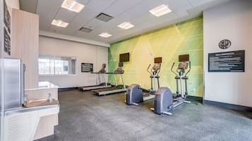 A fitness room with treadmills, stationary bikes, and a wall clock.