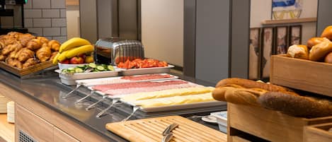 A buffet with various food items including pastries, fruits, and meats.