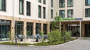 A Holiday Inn Express building with a patio area featuring outdoor seating and greenery.